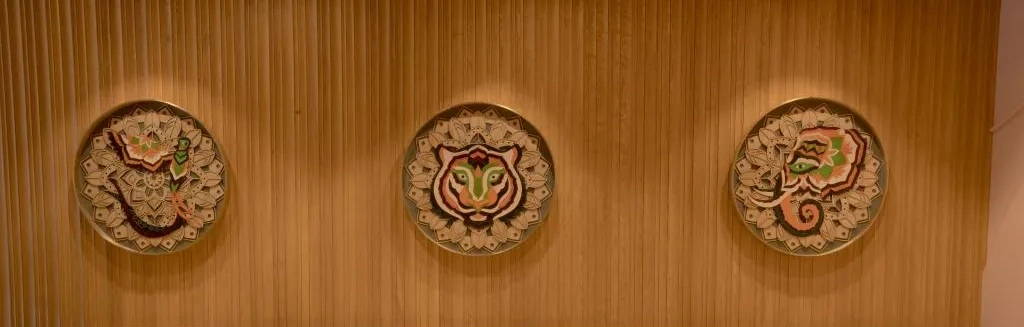 The three embroidered mandala plates — tiger, elephant and quetzal — on the wood-slat wall at Starbucks Model Town, Jalandhar